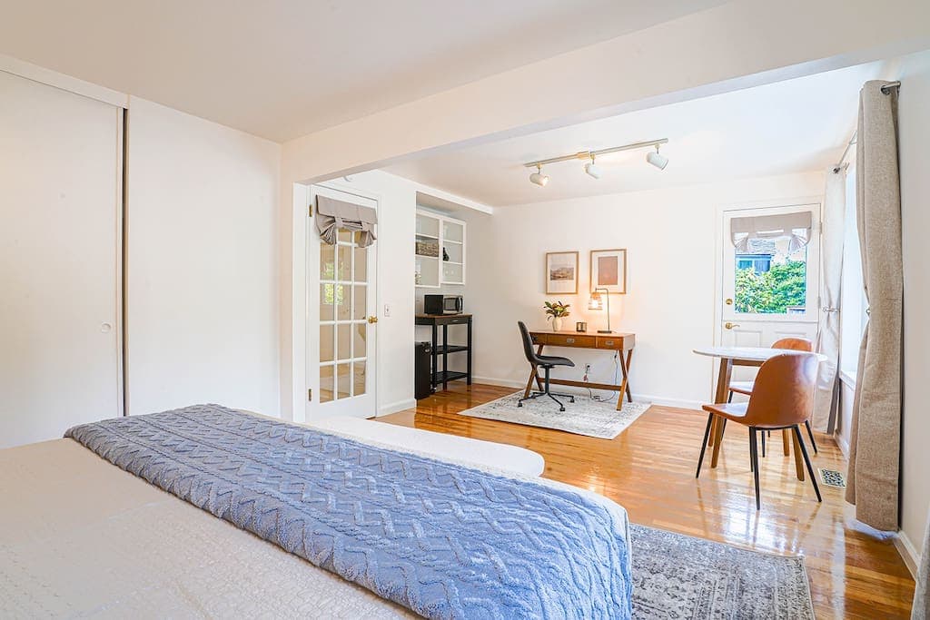 Bright and airy bedroom offers a spacious layout with a cozy sleeping area, dedicated work-from-home space, and a charming sitting nook—perfectly blending comfort and functionality.