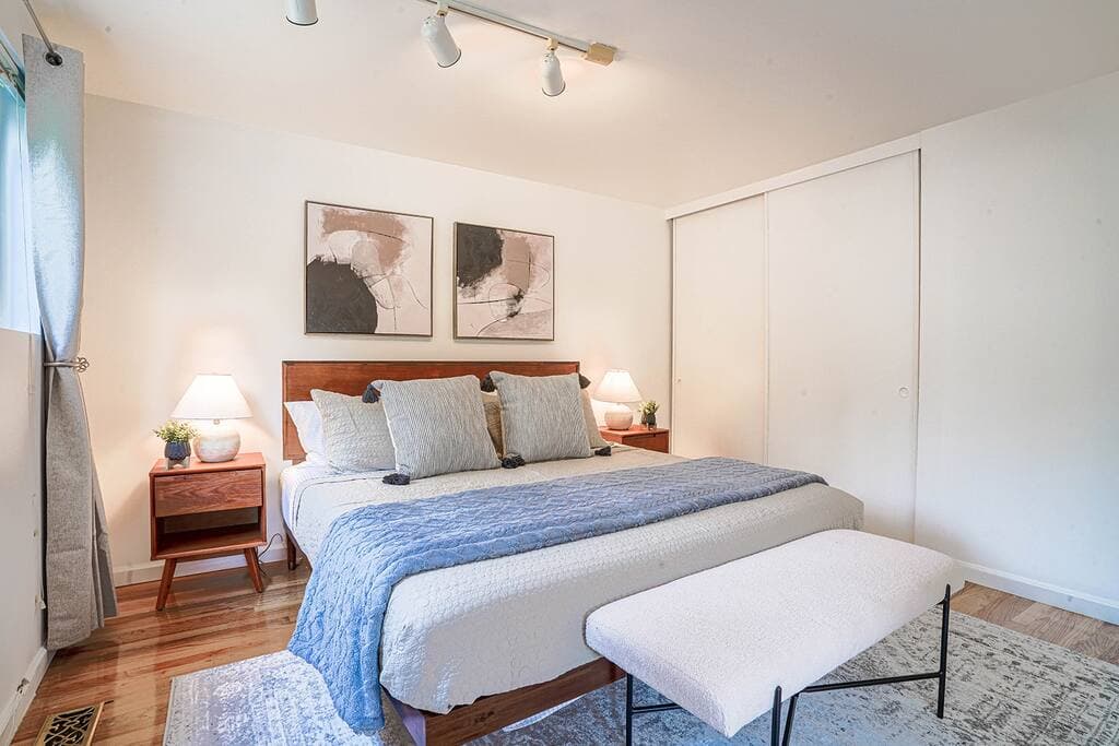 This spacious bedroom features large windows, a dedicated office nook, and a cozy seating area, offering a perfect blend of comfort, functionality, and natural light.