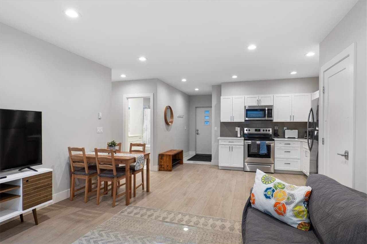 Cozy open-concept unit with a modern kitchen, wooden dining set, and inviting seating—perfect for laid-back meals and movie nights.