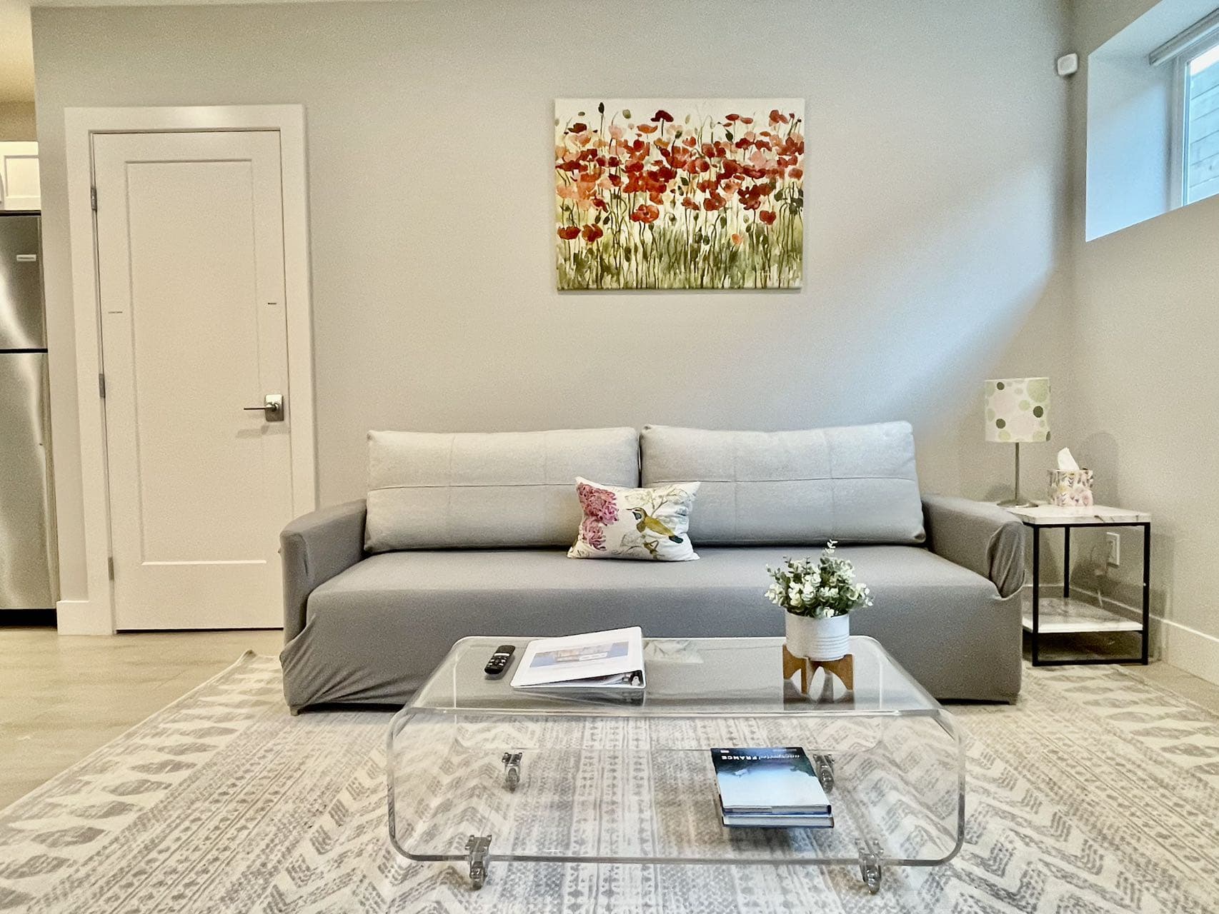Minimalist lounge with a comfy gray sofa, soft lighting, and a sleek acrylic coffee table. A peaceful spot to relax or catch up on reading.