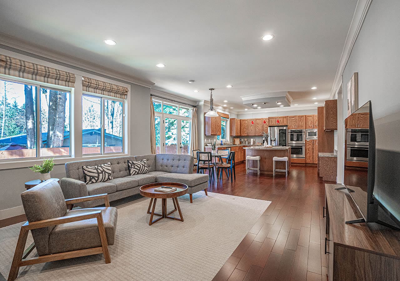 Beautifully open-concept living space features rich hardwood floors, a stylish modern kitchen with stainless steel appliances and a center island, and a cozy, light-filled seating area perfect for entertaining or relaxing.