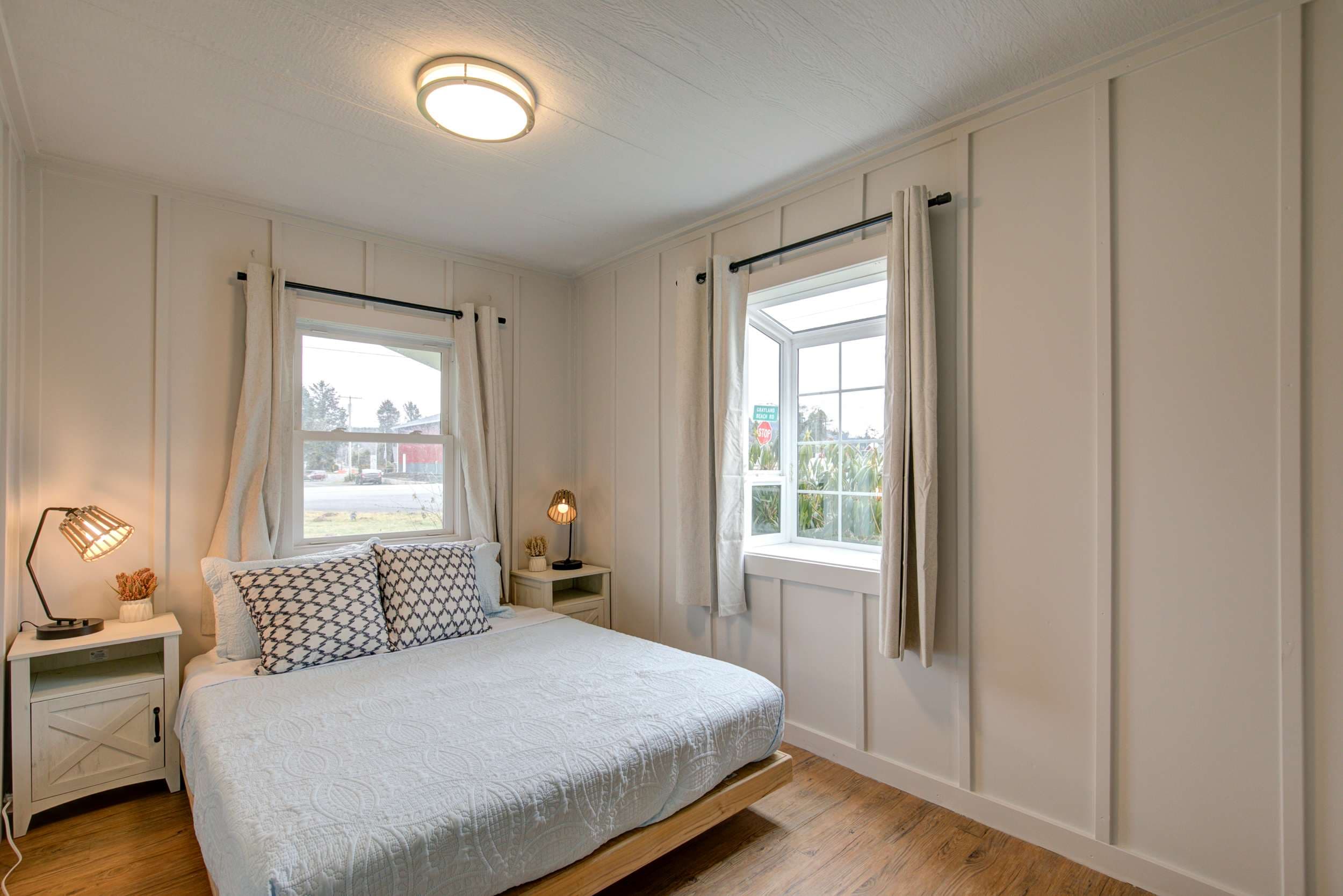 Sunlit serenity: a classy white queen bed by the window, inviting you to dream.