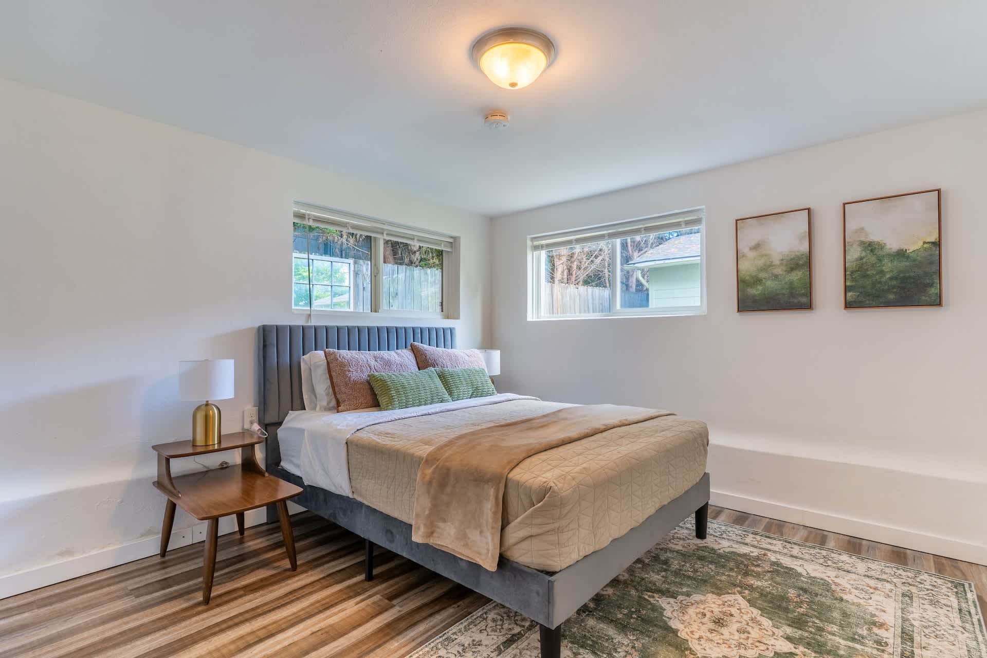 Cozy and modern bedroom featuring a plush upholstered bed with soft bedding and tasteful wall art.